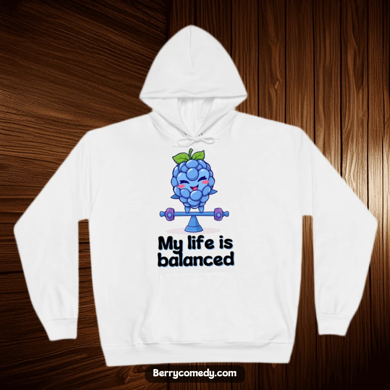 Funny hoodie art of a smiling blue raspberry with a mischievous wink, comically balancing on a teeter-totter, perfect for cozy fun.